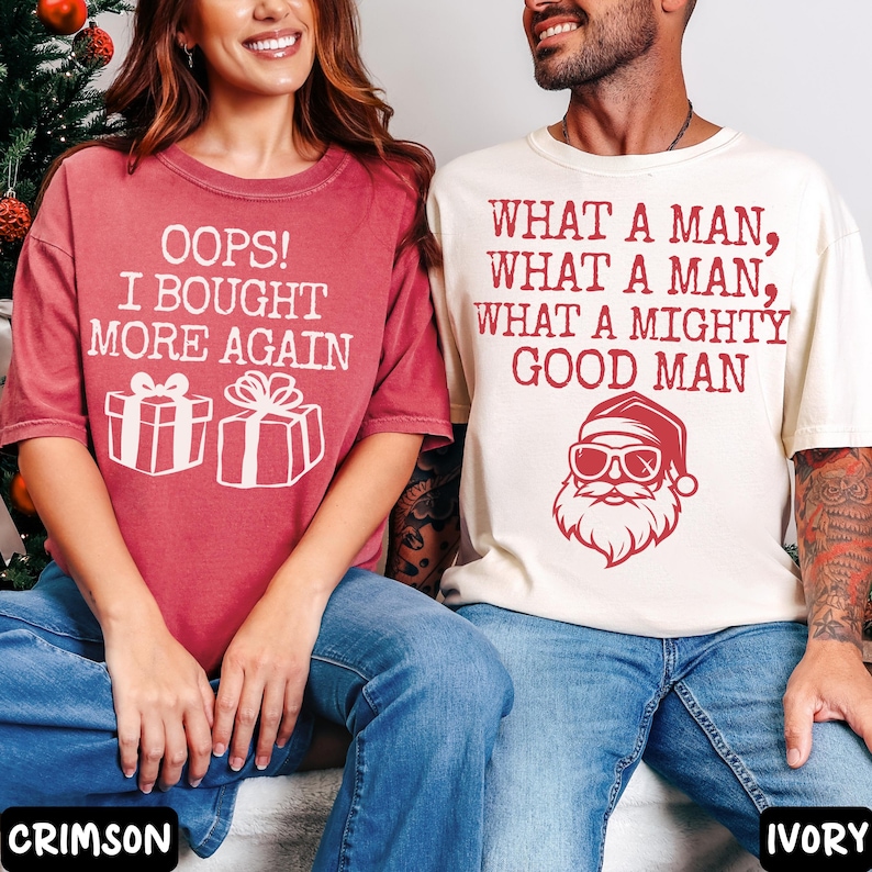 Peut inclure: Deux t-shirts &agrave; manches courtes. L'un est rouge cramoisi avec le texte "OOPS! I BOUGHT MORE AGAIN" et des graphiques de bo&icirc;tes cadeaux. L'autre est ivoire avec le texte "WHAT A MAN, WHAT A MAN, WHAT A MIGHTY GOOD MAN" et un graphique du P&egrave;re No&euml;l.