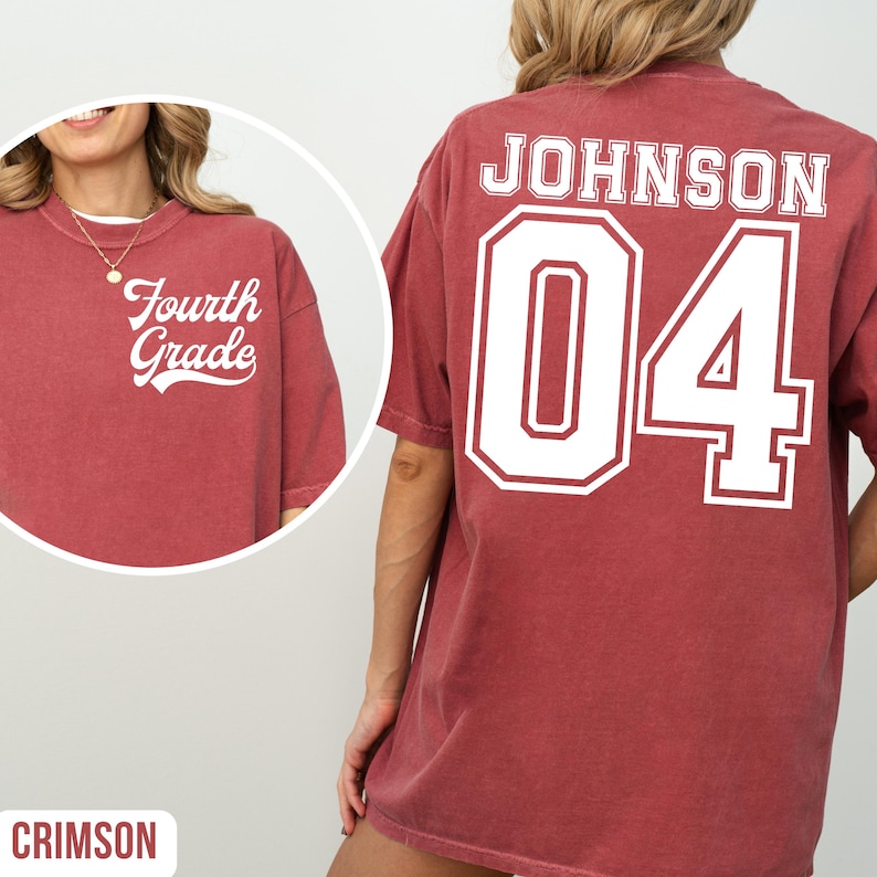 May include: Crimson t-shirt featuring the text "Fourth Grade" on the front and "JOHNSON 04" on the back. The shirt has a faded appearance. The text is in a white, collegiate-style font. The shirt is a casual style.