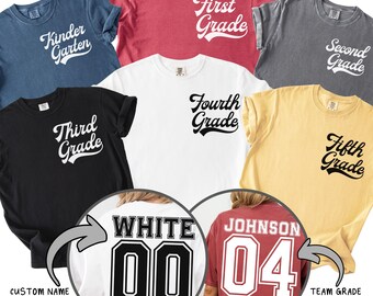 May include: Assorted-color t-shirts with grade level text, including "Kindergarten", "First Grade", "Second Grade", "Third Grade", "Fourth Grade", and "Fifth Grade". Two shirts show custom names and team grades on the back.