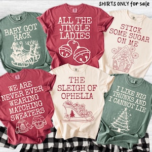 Peut inclure: Plusieurs t-shirts de couleurs vari&eacute;es, chacun orn&eacute; d'un motif et d'un texte sur le th&egrave;me des f&ecirc;tes. Les chemises comportent des phrases telles que "Baby Got Rack", "All the Jingle Ladies" et "I Like Big Trunks and I Cannot Lie."