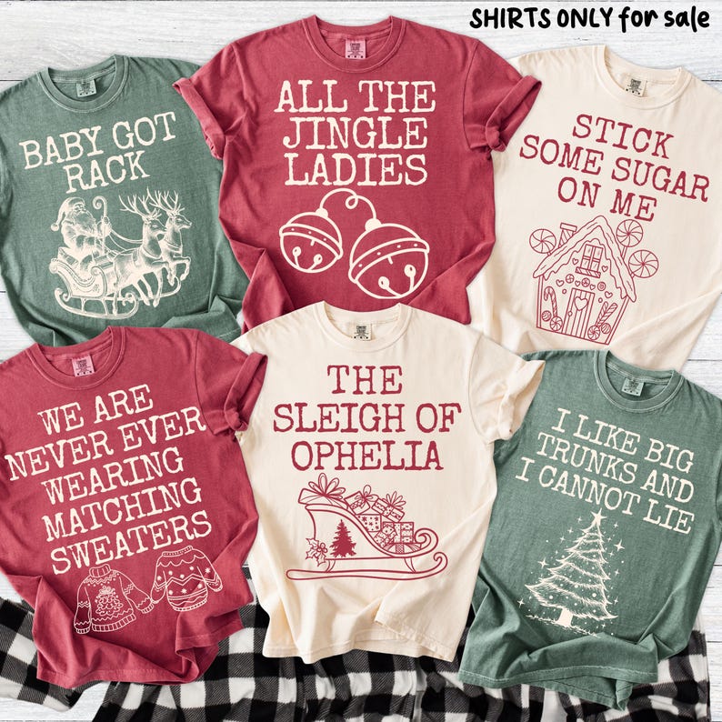 Peut inclure: Plusieurs t-shirts de couleurs vari&eacute;es, chacun orn&eacute; d'un motif et d'un texte sur le th&egrave;me des f&ecirc;tes. Les chemises comportent des phrases telles que "Baby Got Rack", "All the Jingle Ladies" et "I Like Big Trunks and I Cannot Lie."