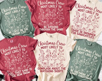 May include: A collection of six t-shirts in various colors, each featuring a flamingo design with holiday-themed text. The shirts have the text "Christmas Crew Most Likely To" with different phrases below. The shirts are displayed on a black and white checkered surface.