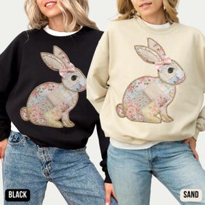 May include: Two sweatshirts with a patchwork bunny design. The sweatshirt on the left is black and the sweatshirt on the right is sand.