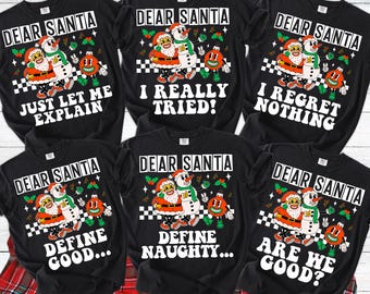 May include: Black graphic t-shirts with the text "DEAR SANTA" and various phrases like "JUST LET ME EXPLAIN" and "I REGRET NOTHING." Each shirt features a cartoon Santa Claus and snowman design with Christmas ornaments.