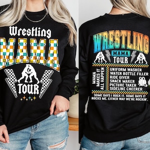 May include: Black sweatshirt with the text "Wrestling Mama Tour" in rainbow colors. The front of the sweatshirt has a checkered design with the text "Wrestling Mama Tour" in white and yellow.