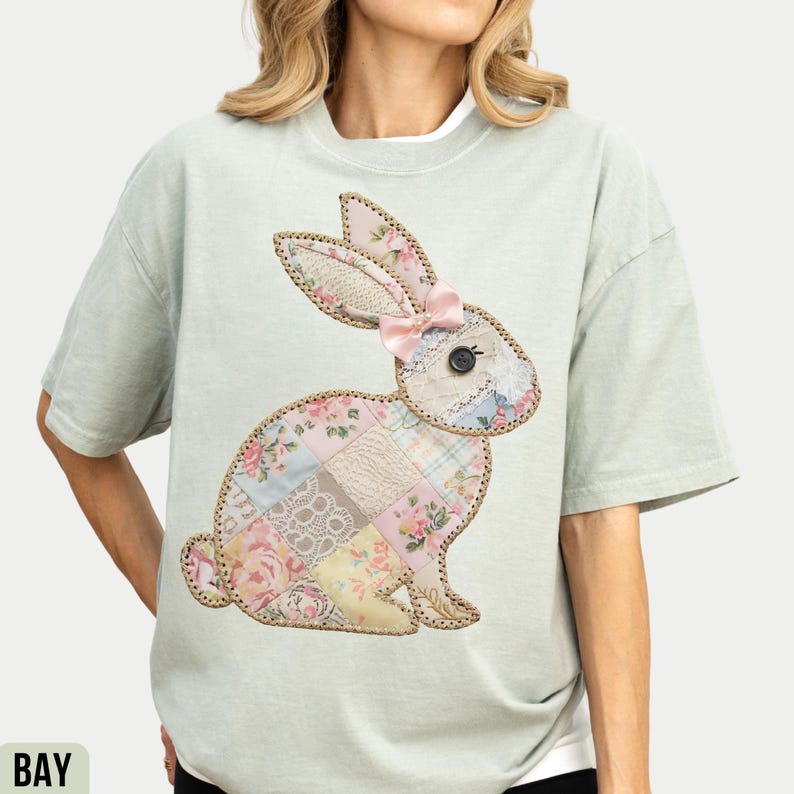 May include: A light green t-shirt with a patchwork bunny applique. The bunny is made of various floral and lace fabrics and has a pink bow.