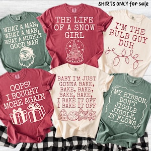 Peut inclure: Plusieurs t-shirts de couleurs vari&eacute;es, chacun avec un graphisme et un texte sur le th&egrave;me des f&ecirc;tes. Les chemises pr&eacute;sentent des phrases comme "The Life of a Snow Girl" et "I'm the Bulb Guy Duh."