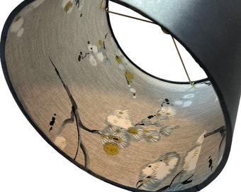 May include: A black lampshade with a floral pattern on the inside. The pattern features white, blue, and yellow flowers on a gray background.