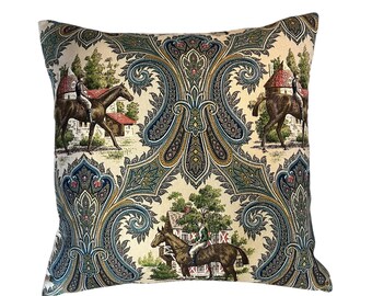 May include: Square decorative pillow with a cream-colored background featuring a repeating pattern of riders on horseback, houses, and paisley designs in shades of blue, green, and gold. The pillow has a soft, textured appearance.