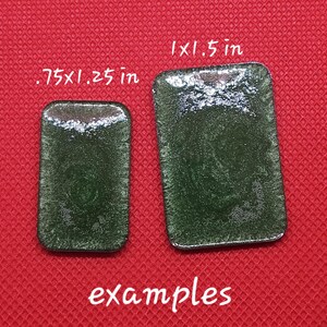 May include: Two rectangular green glass tiles with a sparkly finish. The smaller tile measures .75 x .25 inches and the larger tile measures 1 x 1.5 inches.  Examples.