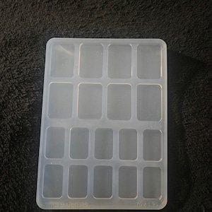 May include: A clear plastic mold with 16 rectangular compartments. The mold is labeled "Mini Markers" and "7.5 x 1.25".