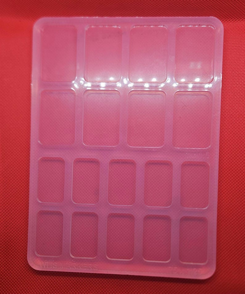 May include: A clear plastic mold with 16 rectangular compartments. The mold is designed for making small crafts or resin projects.