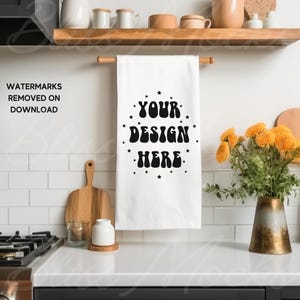 May include: White kitchen towel with black text that reads "YOUR DESIGN HERE" surrounded by small black stars.