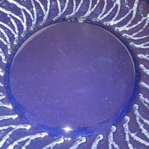 Pode incluir: Um prato de cerâmica azul com um design branco. O design é uma série de linhas que irradiam do centro do prato.