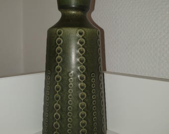 Può includere: Un vaso in ceramica verde con un motivo testurizzato di cerchi. Il vaso ha una base larga e un collo stretto.