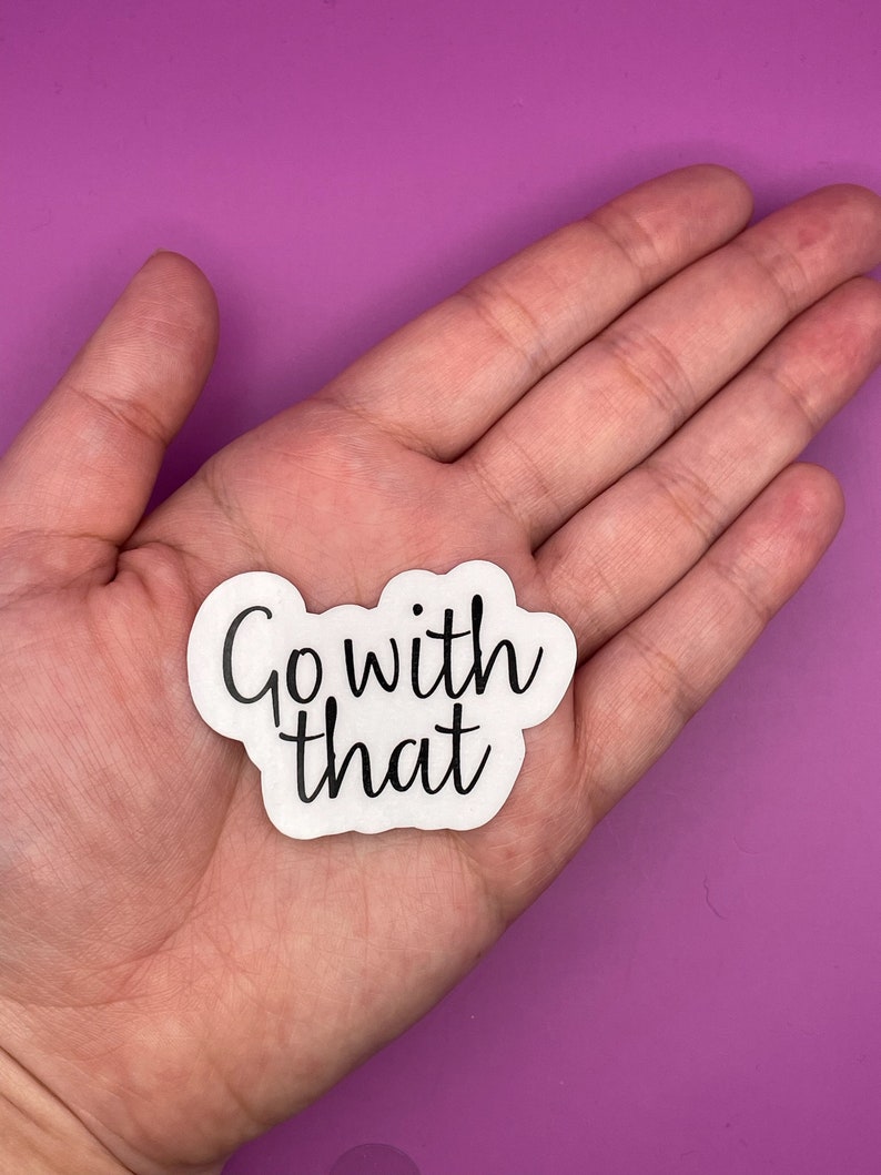 May include: White sticker with black text that reads "Go with that" on a pink background.