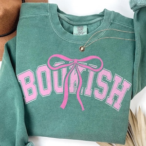 May include: A green sweatshirt with a pink bow and the word "BOUTIQUE" printed on the front.