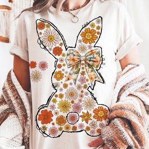 Puede incluir: Camiseta blanca con un dise&ntilde;o de conejo floral. El conejo est&aacute; delineado en negro y tiene un gran lazo hecho de tela floral.