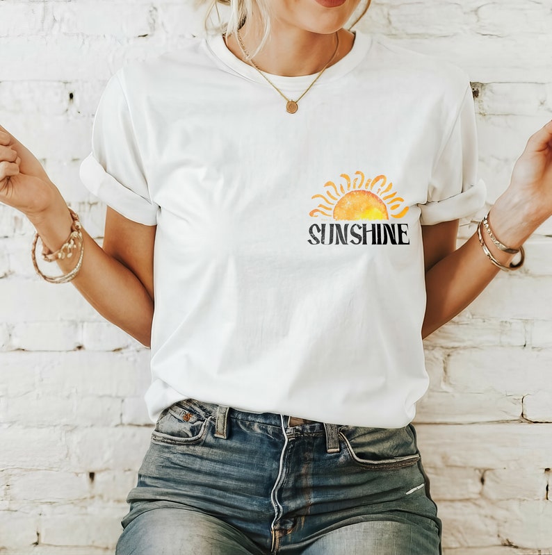 May include: White t-shirt with a watercolor-style sun graphic and the word "SUNSHINE" printed in black.