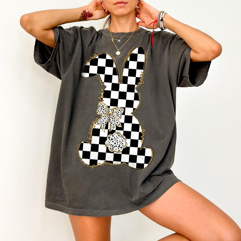 May include: A charcoal gray oversized t-shirt with a black and white checkered bunny graphic. The bunny has a large bow with white polka dots.