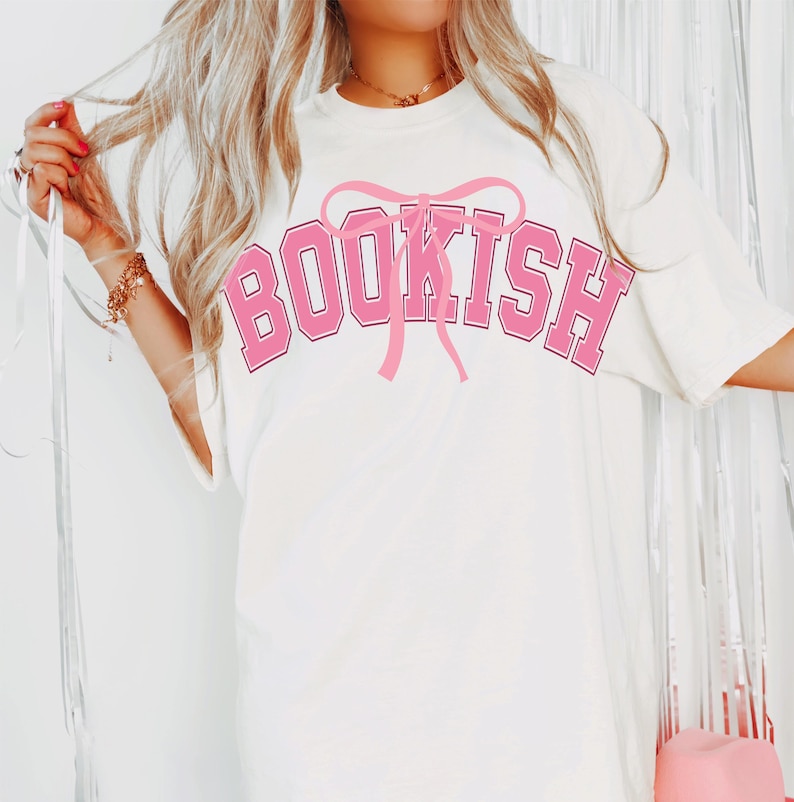 May include: White t-shirt with a pink graphic that says "BOOKISH" with a pink bow on top.