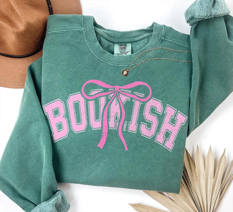 May include: A green sweatshirt with a pink bow and the word "BOUTIQUE" printed on the front.