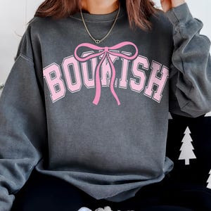 May include: A gray sweatshirt with a pink bow and the word "BOUSH" printed on the front.