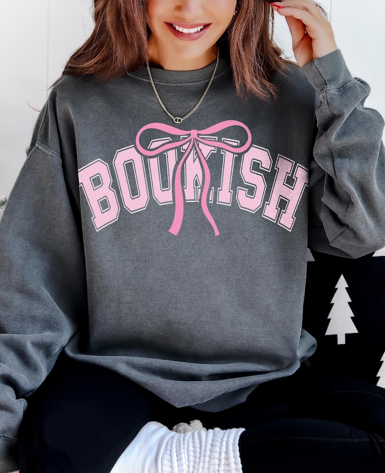 May include: A gray sweatshirt with a pink bow and the word "BOUSH" printed on the front.