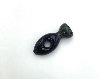 May include: A small, dark blue glass pipe shaped like a fish with a hole in the middle. The pipe has a swirl pattern on the top.