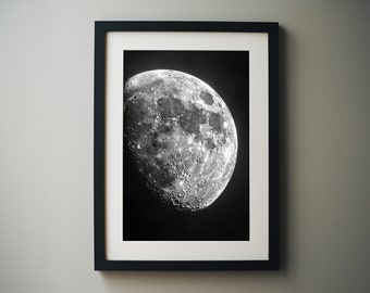 May include: A black and white photograph of a crescent moon against a dark background. The moon is the main focus of the image and is shown in detail, with its craters and surface features visible.