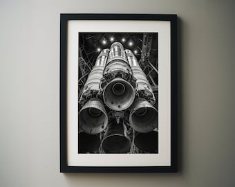 Könnte beinhalten: Ein Schwarzweißfoto eines Raketenmotors mit mehreren Düsen, von unten betrachtet. Der Motor befindet sich in einem Hangar mit Oberlicht.