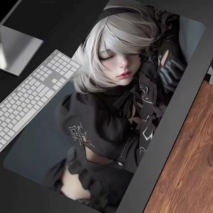 Może przedstawiać: Prostokątna podkładka pod mysz z szczegółową ilustracją postaci ze srebrnymi włosami i czarnym strojem. Postać jest przedstawiona z zamkniętymi oczami, spoczywająca na ciemnym tle. Klawiatura jest widoczna w lewym górnym rogu.