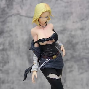 May include: A figurine of a female character with short blonde hair, wearing a torn black top, a blue jacket, and black leggings. The figure has a silver chain belt and a black choker. The figure is posed with a serious expression.
