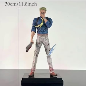 May include: A detailed figurine of a character, 11.8 inches tall, in a blue shirt, gray pants, and brown boots. The figure holds a weapon and a blue energy effect. The figure is standing on a black base.