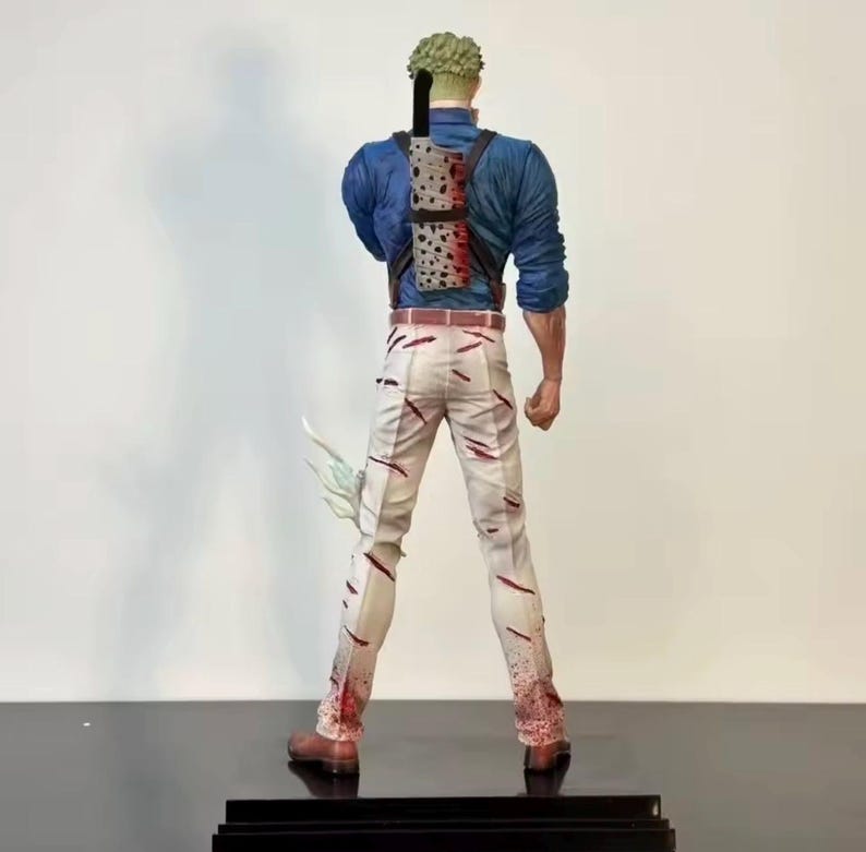 May include: A figurine of a character from an anime series, viewed from the back. The figure wears a blue shirt, white pants with red streaks, and brown boots. A sheath with swords is strapped to the back. The figure has green hair.