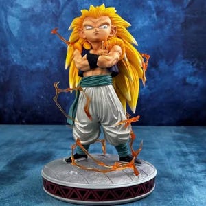 May include: A detailed figurine of a character with spiky yellow hair, wearing a dark blue top, white trousers, and a green sash. The figure is posed with arms crossed, standing on a round base with a red and grey design. Orange energy effects surround the figure.