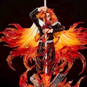 Könnte beinhalten: Detaillierte Figur einer Figur mit feuerrotem Haar und schwarzer Uniform, die ein Schwert hält. Die Figur ist von durchscheinenden orangefarbenen und roten Flammen umgeben, mit einem weißen Umhang. Der Sockel hat japanischen Text.