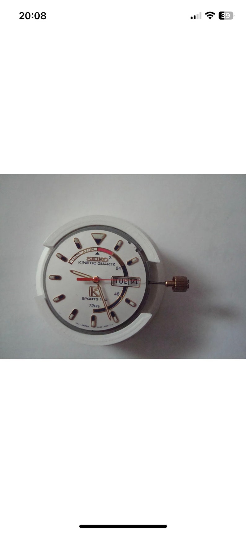 Puede incluir: Una esfera de reloj Seiko Kinetic Quartz blanca con marcas negras y una aguja de segundos roja. La esfera tambi&eacute;n muestra el d&iacute;a de la semana, "TUE", y la fecha, "14".