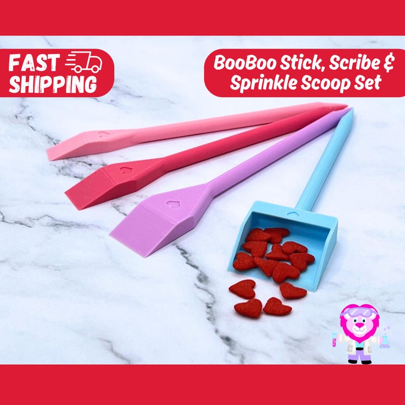 May include: A set of three pink, purple, and blue plastic tools for spreading frosting or sprinkles. The tools are shaped like a spatula with a heart-shaped handle. A blue plastic scoop with a heart-shaped handle is filled with red heart-shaped sprinkles. The tools are on a white marble surface. BooBoo Stick, Scribe & Sprinkle Scoop Set
