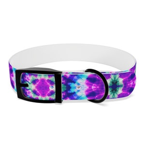 Op de afbeelding: Een witte en zwarte hondenriem met een tie-dye patroon in tinten paars, blauw en groen.