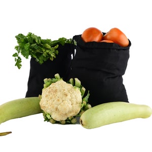 May include: Three black reusable produce bags filled with fresh produce, including tomatoes, cauliflower, and a long green gourd. The bags are made of a soft, durable fabric and are perfect for carrying groceries.