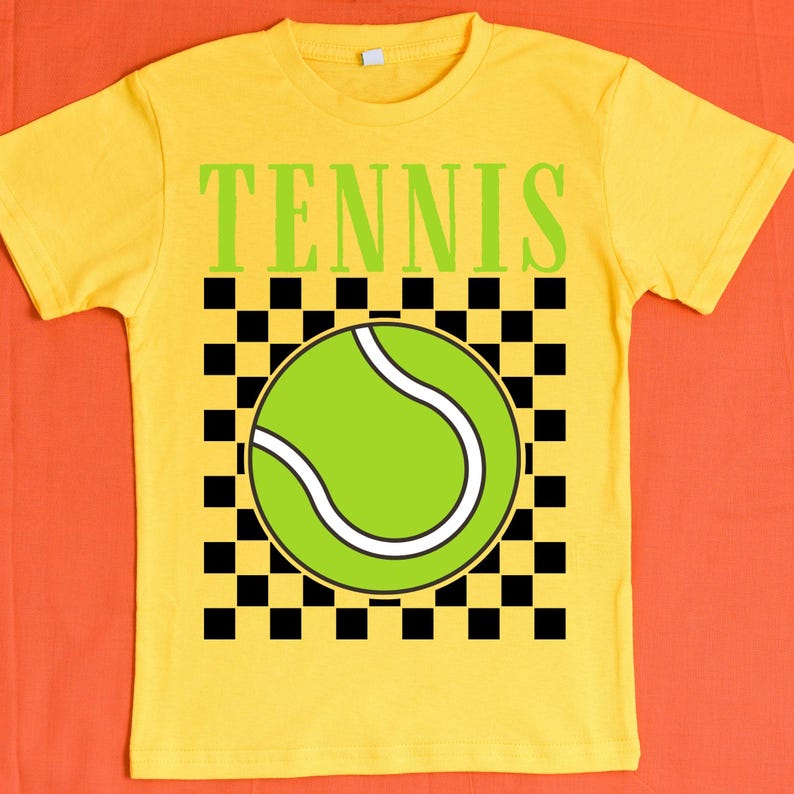 May include: Yellow t-shirt with a black and white checkered pattern and a green tennis ball graphic. The text "TENNIS" is printed in black letters above the graphic.