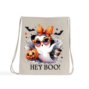 Könnte beinhalten: Beiger Kordelzugbeutel mit einem Cartoon-Geist, der eine Sonnenbrille und eine Schleife trägt, eine Kaffeetasse und einen Kürbis hält. Die Worte "HEY BOO!" sind darunter gedruckt. Fledermäuse und Sterne schmücken den Hintergrund. Halloween-Thema.