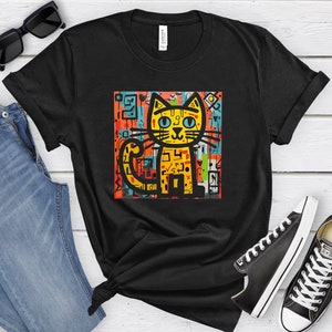 May include: Black t-shirt with a colorful graphic of a cat with blue eyes. The cat is surrounded by abstract shapes and lines.