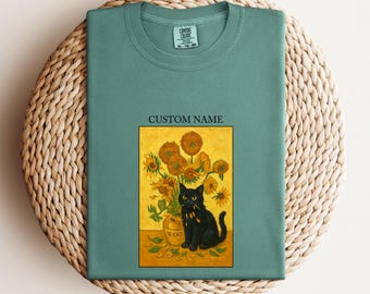 May include: Light green t-shirt with a graphic of a black cat sitting in front of a vase of sunflowers. The graphic is in a rectangular frame with the text "CUSTOM NAME" above it. The text "LIGHT GREEN" is at the bottom.