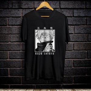 May include: Black t-shirt with a white graphic of a character from the anime Jujutsu Kaisen. The character has white hair and is wearing a black and white outfit. The text "五条悟" and "GOJO SATURU" are printed on the shirt.