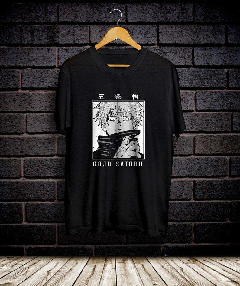 May include: Black t-shirt with a white graphic of a character from the anime Jujutsu Kaisen. The character has white hair and is wearing a black and white outfit. The text "五条悟" and "GOJO SATURU" are printed on the shirt.