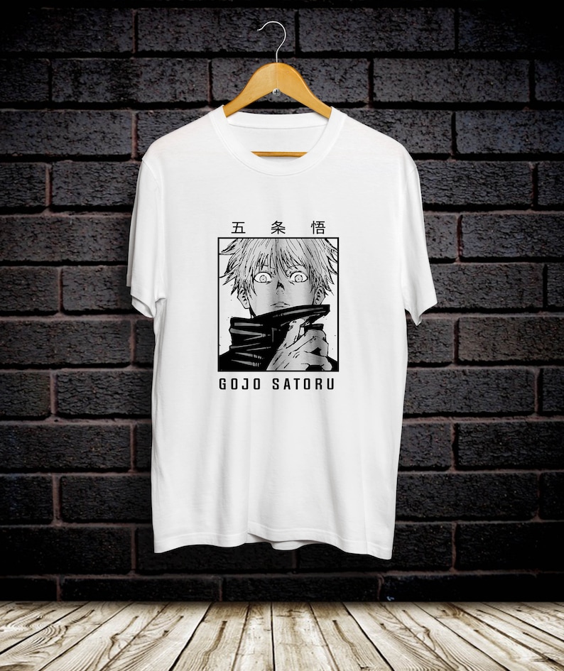 May include: White t-shirt with a black and white illustration of a character from the anime Jujutsu Kaisen. The character is Gojo Satoru, and the text "Gojo Satoru" is printed below the illustration. The text "五条悟" is printed above the illustration.