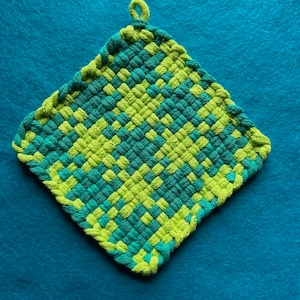 Könnte beinhalten: Ein gewebter Topflappen in Diamantform, grün und blau.