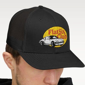 May include: Black trucker hat featuring a yellow and red oval with a white car graphic and the text "FlatSix Club". The hat has a mesh back and a curved brim.